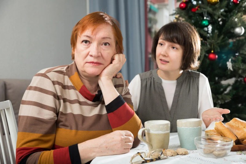 A red-haired, middle aged woman gazes off in the distance while her brunette companion urgently shares divergent political views.