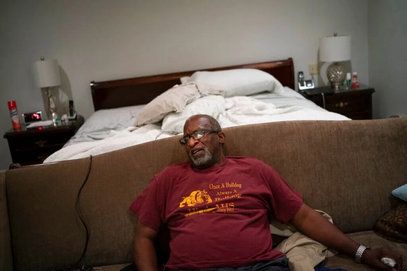 a man sitting in his bedroom sick with COVID-19 with no family around to help