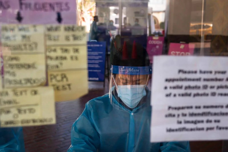 healthcare worker at a testing site as COVID-19 death tolls rise