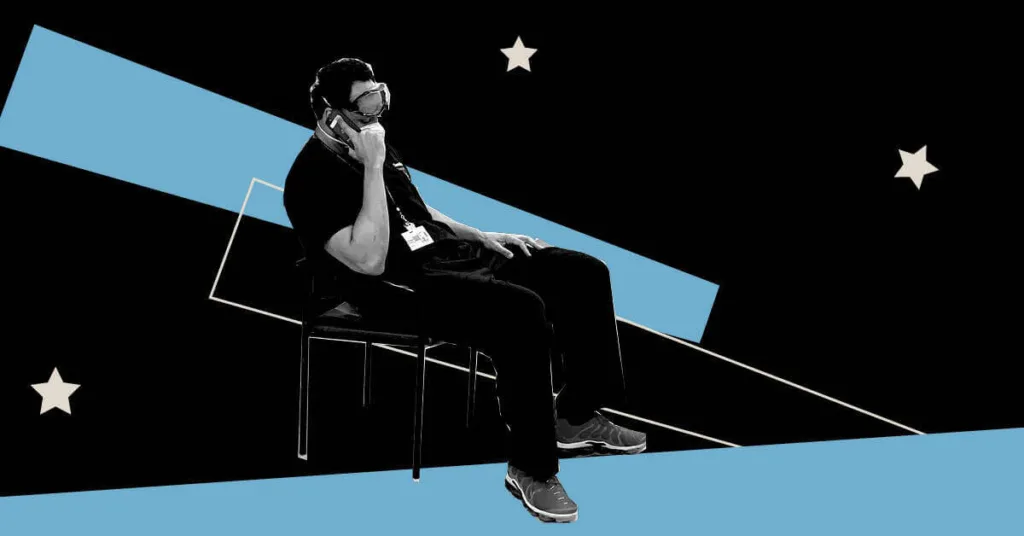 ER doctor wearing scrubs sitting in chair with hand on his head