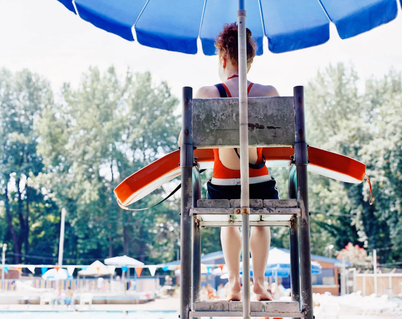 Teenage female lifeguard (14-16) watching pool, rear view Teenage female lifeguard (14-16) watching pool, rear view