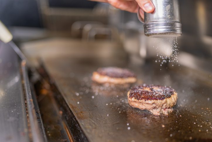 Chef salting the burgers in the restaurant kitchen