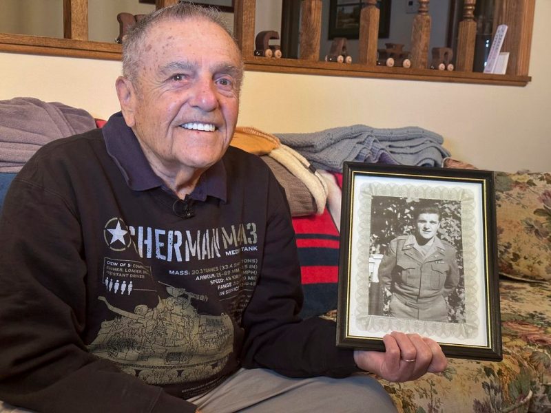 World War II veteran Andy Negra, a native of Western Pa., sits in his home in Helen, Ga, on April 10, 2024. He shows a photo of himself during his time with the Army's 128th Armored Field Artillery Battalion, 6th Armored Division.
