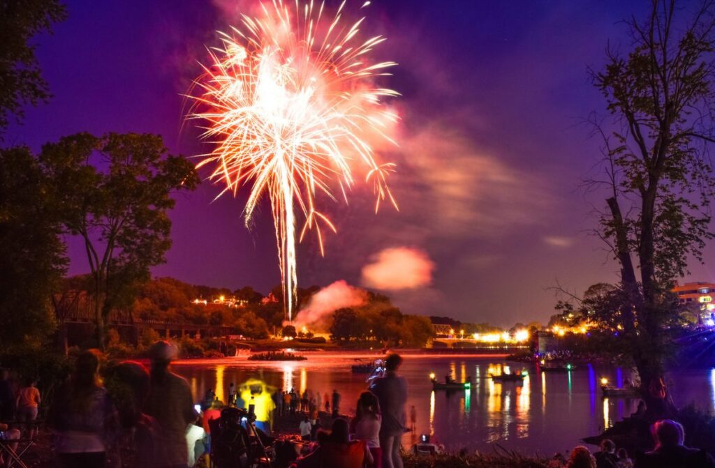 This is a 15 second exposure shot from Phillipsburg NJ looking towards the Forks in Easton Pennsylvania by the River. There are private and fire/rescue boats in the river.The streaks of light are due to long exposure if you zoom in to look at the larger version on the right you will see little white dots on bottom lower middle right of the photo, those are lights from smartphones recording the event.