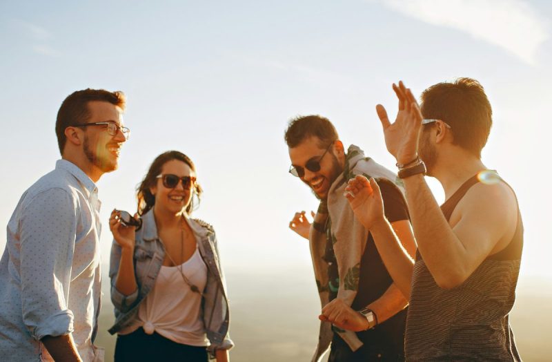 Group of young people laughing and talking in the sunshine.