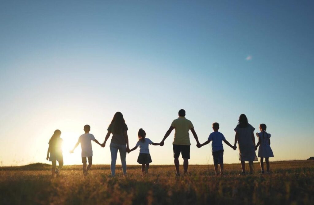 Silhouettes of a family holding hands outside.