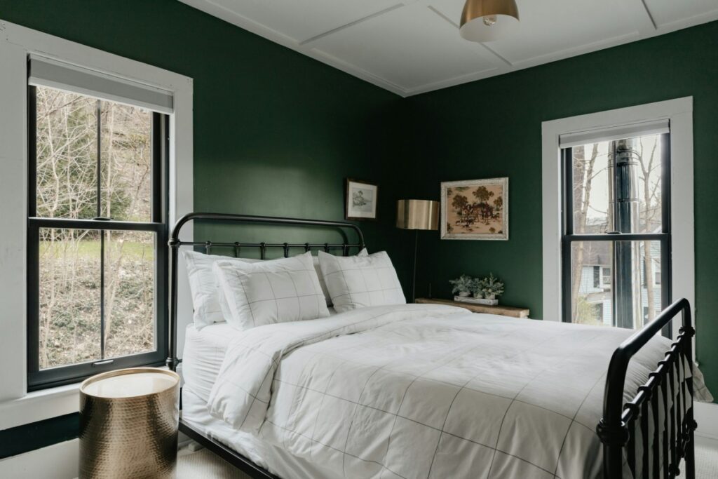 Bed with white sheets in a dark green colored room.