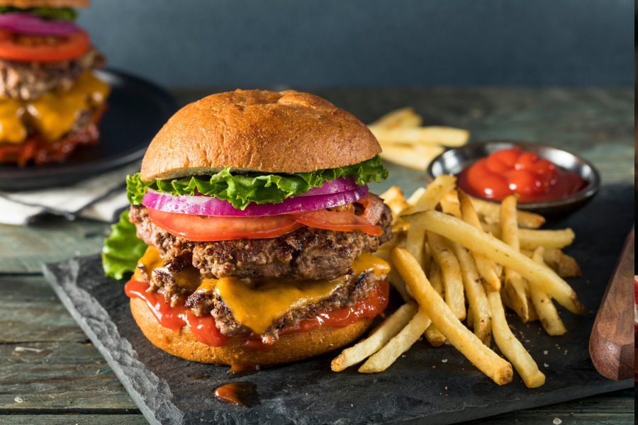 A very large burger with fries.