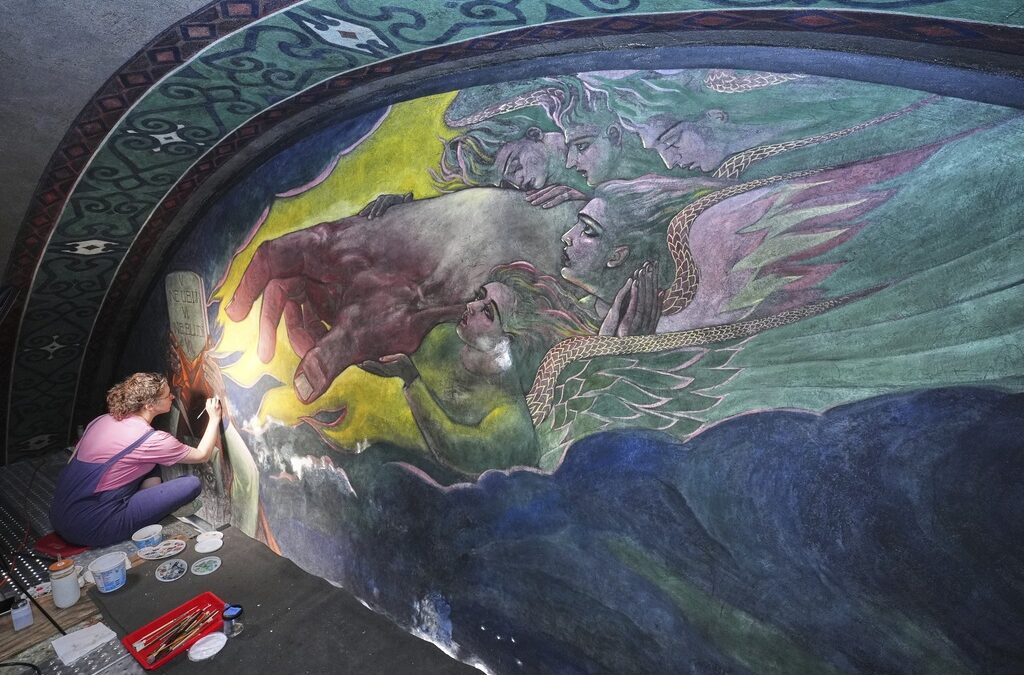 Inside a historic church painted with murals that reflect searing social commentary