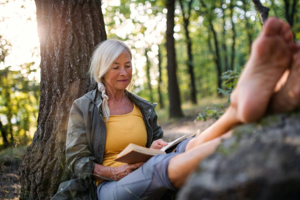 a white woman sits in a hammock reading a book outdoors