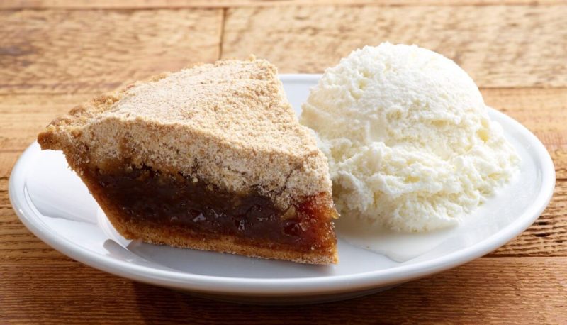 a slice of shoofly pie with vanilla ice cream on a white plate