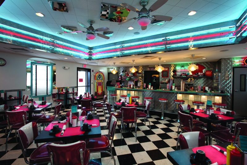 a themed diner with a black and white floor and neon lights