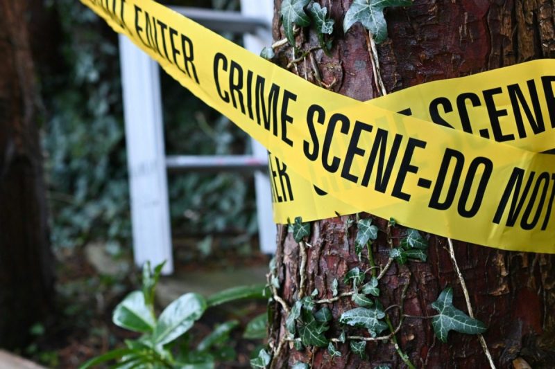 yellow and black crime scene tape around a tree outside