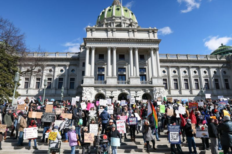 HARRISBURG, PENNSYLVANIA, UNITED STATES - 2025/02/17: A participant protesting against the Trump Administration and Elon Musk holds placards outside of the Pennsylvania Capitol. The "No Kings Day" protest, organized by the 50501 movement on Presidents Day, was part of a nationwide demonstration against the Trump administration and Elon Musk.