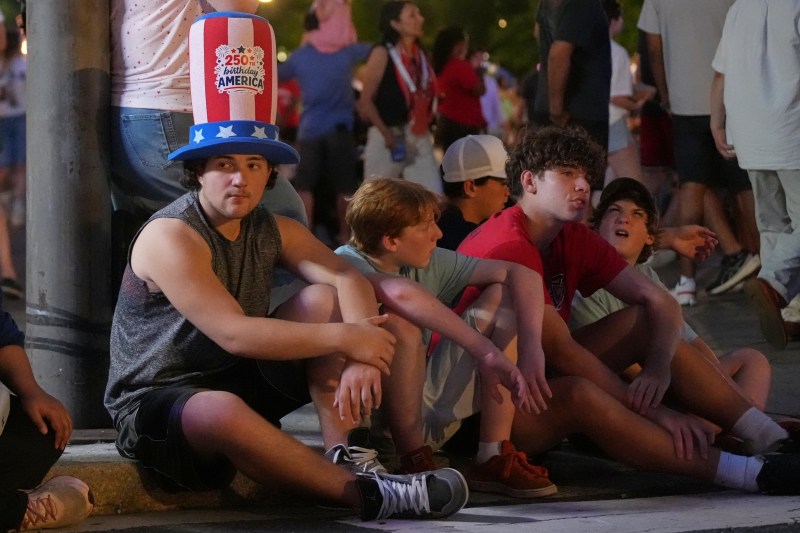 Photo of people sitting down on the sidewalk on July 4, 2026